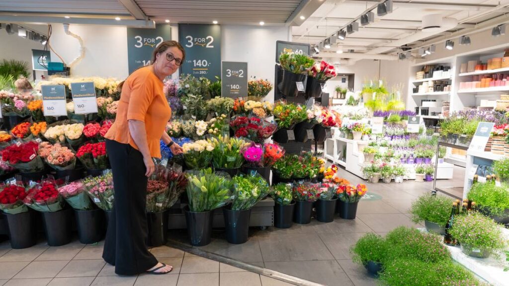 HR-direktør i Meste grønn Rita Bondeson Børke foran blomster.