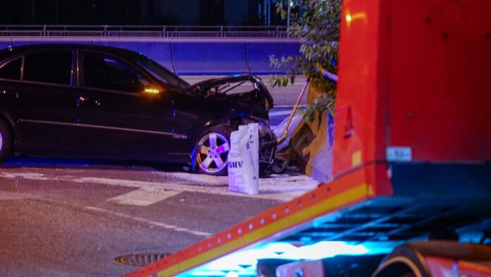 En bil har kjørt inn i murvegg og man ser tydelige materielle skader foran på bilen. 