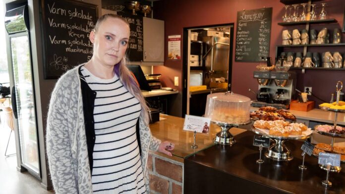 Marthe Syrstad Kofstad står foran kassen i en kafe. Hun har på seg en stripete kjole og ser inn i kamera. 